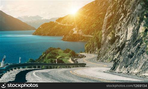 Winding road along mountain cliff and lake landscape in Queenstown, New Zealand South Island. Travel and road trip in summer.