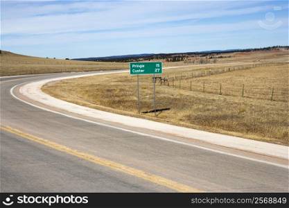 Winding road in South Dakota with mileage distance road sign.