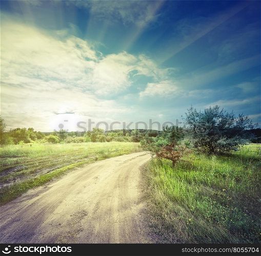 Winding sandy road in field under the daylight sky. Winding sandy road in field