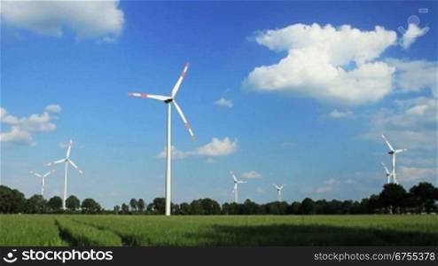 Windkraftanlagen vor blauem Himmel, Niedersachsen, Deutschland. Die Wolken ziehen in Echtzeit nber die Kamera hinweg in Richtung Horizont.