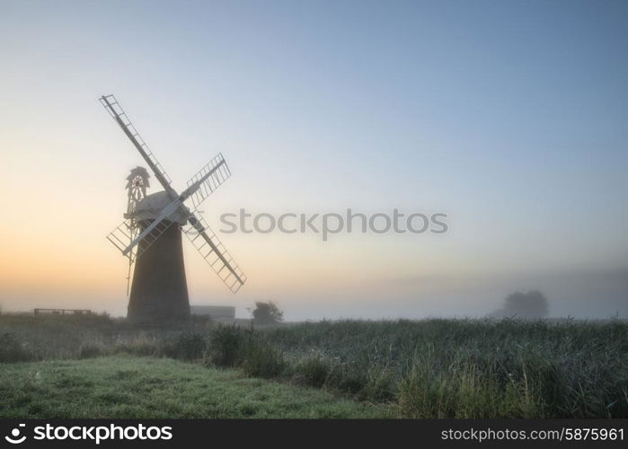 Windmill in stunning landscape on beautiful Summer sunrise