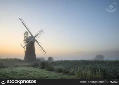 Windmill in stunning landscape on beautiful Summer sunrise