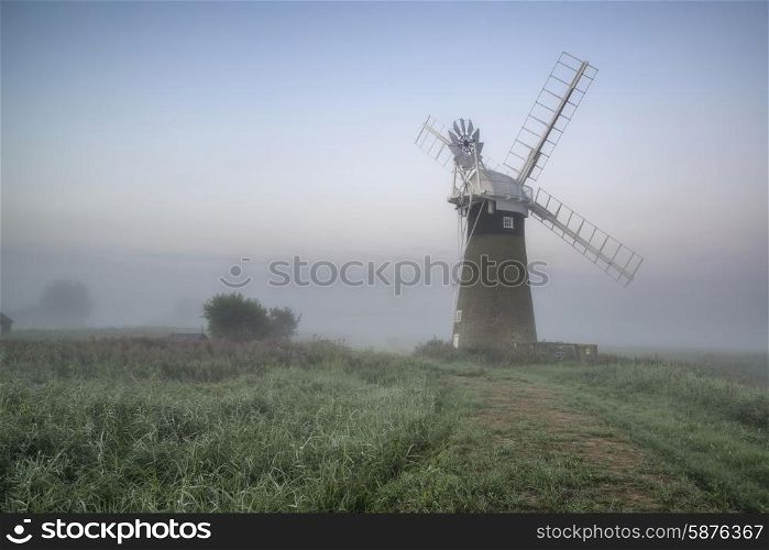 Windmill in stunning landscape on beautiful Summer sunrise