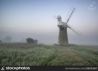 Windmill in stunning landscape on beautiful Summer sunrise