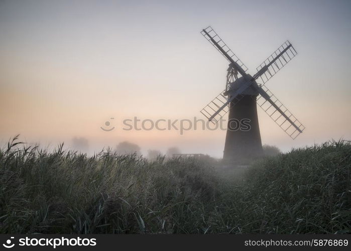 Windmill in stunning landscape on beautiful Summer sunrise