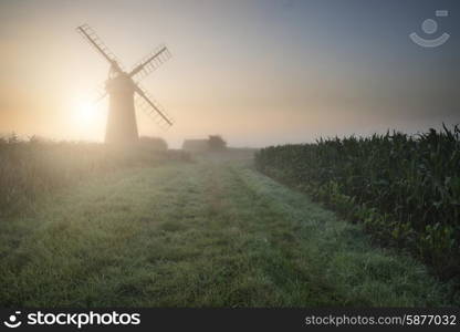 Windmill in stunning landscape on beautiful Summer sunrise