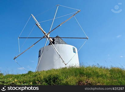 Windmill on a hill in front of blue sky