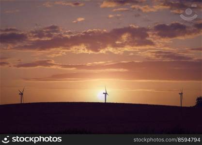 Windmill silhouettes on a hill in a beautiful sunset with dramatic sky