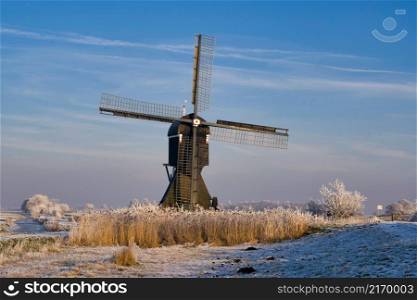 Windmill the Broekmolen near the Dutch village Streefkerk under a blue sky in a winter landscape. Windmill the Broekmolen near the Dutch village Streefkerk