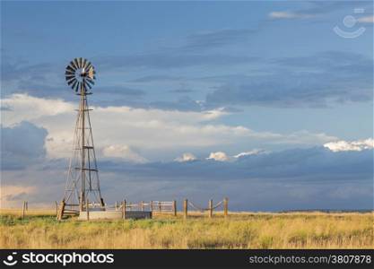 windmill with a pump and cattle water tank in shortgrass prairie, iPawnee National Grassland in Colorado near Grover