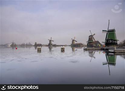 Windmills along the river Zaan in the Dutch traditional village Zaanse Schans which is one of the busiest tourist locations in the Netherlands. Windmills along the river Zaan