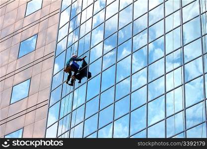 window cleaner hanging on rope at work on skyscraper