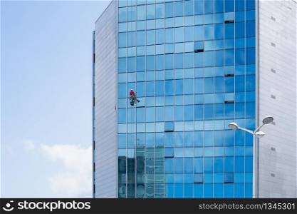 Window cleaner working on a glass facade suspended. Cleaning concept. Copy space
