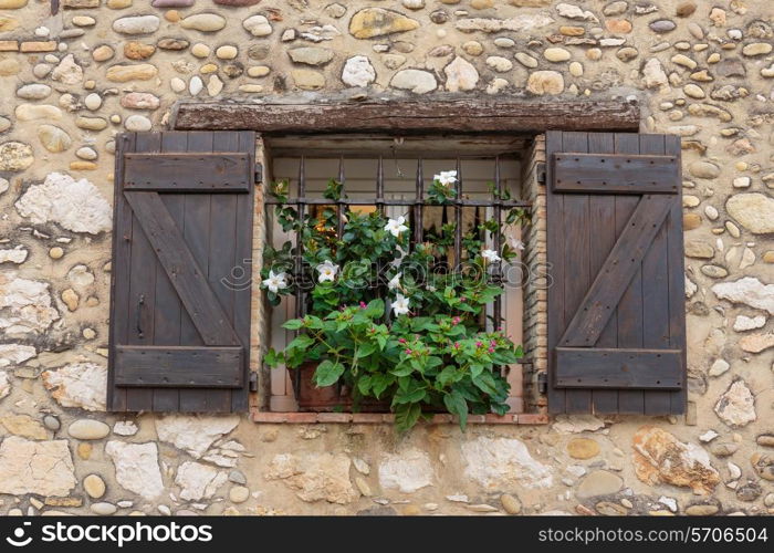 Window in an old house decorated with flower pots and flowers