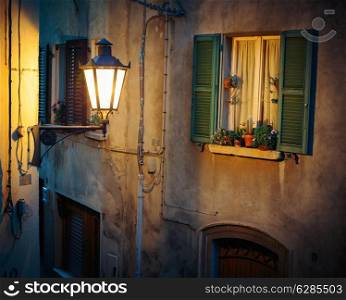 Window in an old house decorated with flower pots and flowers at night