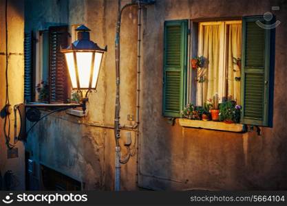Window in an old house decorated with flower pots at night