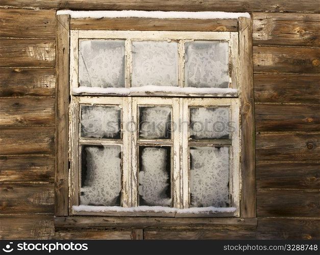 Window of abandoned country log house in russian village on winter sunny day