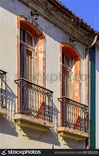 Window of old colonial style house with balcony and colorful frame with peeling paint in the ancient city of Ouro Preto in Minas Gerais, Brazil. Window of old colonial style house with balcony and colorful frame
