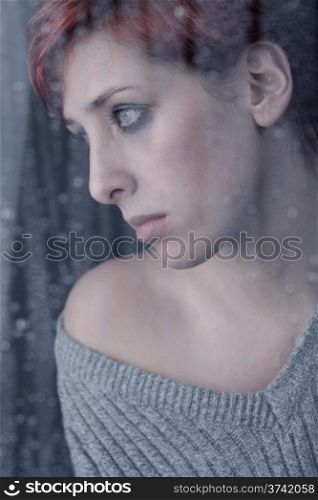 window sadness. beautiful sad woman behind window at a rainy day
