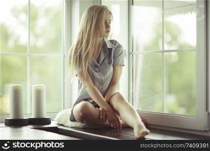 Window sitting young adult girl at home