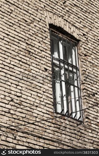 Window with bars on rear brick old house wall
