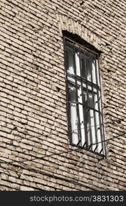 Window with bars on rear brick old house wall