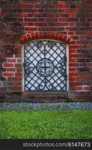 Window with grid in the old red brick wall