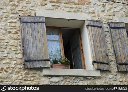 Window with wooden shutters and flowers and plants