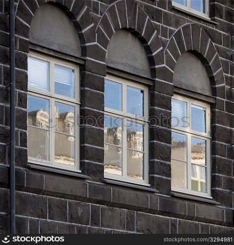 Windows in brick building reflecting buildings opposite