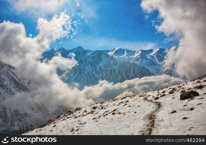 Windows of clouds in mountains. Beautiful misty rock landscape with snow and clouds. Great view of the foggy Ala-Archa National Park in Kyrgyzstan.