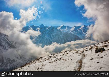 Windows of clouds in mountains. Beautiful misty rock landscape with snow and clouds. Great view of the foggy Ala-Archa National Park in Kyrgyzstan.