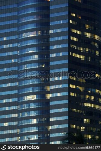windows of office buildings illuminated at night for background