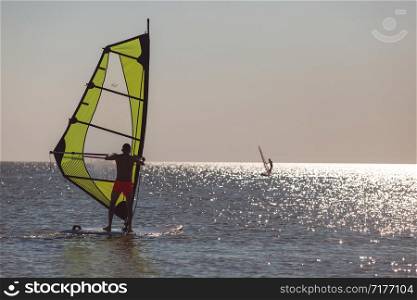 Windsurfers in the sea during sunset, active lifestyle.. Windsurfers in the sea during sunset, active lifestyle