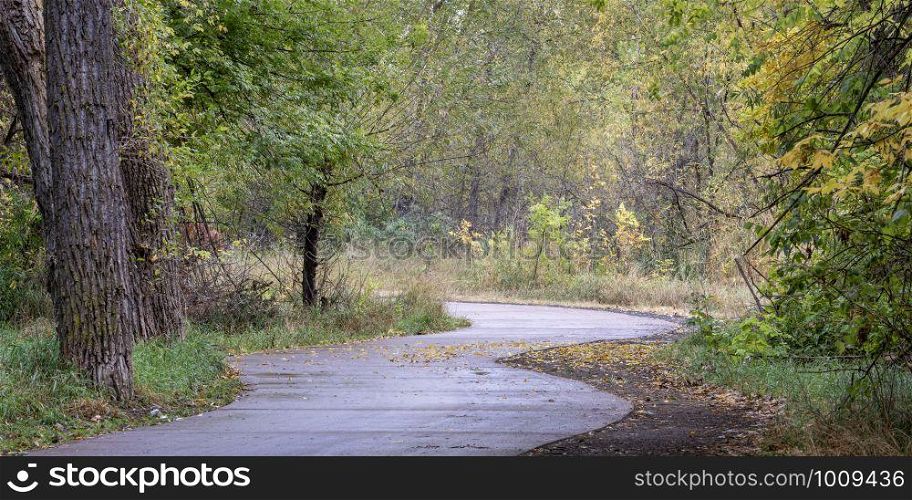 windy bike trail along the Poudre River in Fort Collins, Colorado - rainy day with fall colors, panoramic format