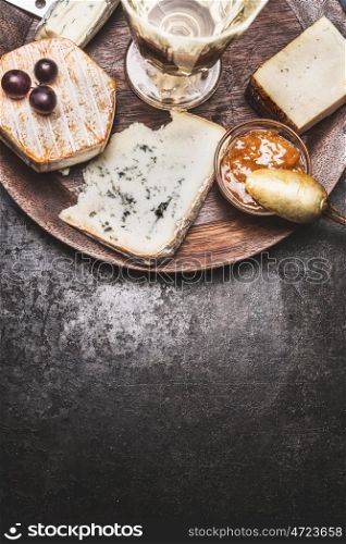 Wine and cheese on dark rustic background, top view, border