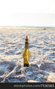 wine and glasses standing in the sand on the beach. wine and glasses standing in sand on the beach