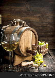 Wine background. A barrel of white wine with branches of green grapes. On a wooden background.. Wine background. A barrel of white wine with branches of green grapes.