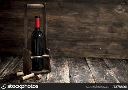 Wine background. A bottle of red wine on a stand with a corkscrew. On a wooden background.. Wine background. A bottle of red wine on a stand with a corkscrew.
