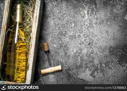 Wine background. A bottle of white wine in an old box. On a rustic background.. Wine background. A bottle of white wine in an old box.