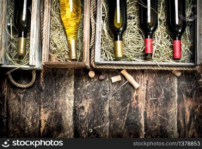 Wine background. Bottles of red and white wine in old boxes. On a wooden background.. Wine background. Bottles of red and white wine in old boxes.
