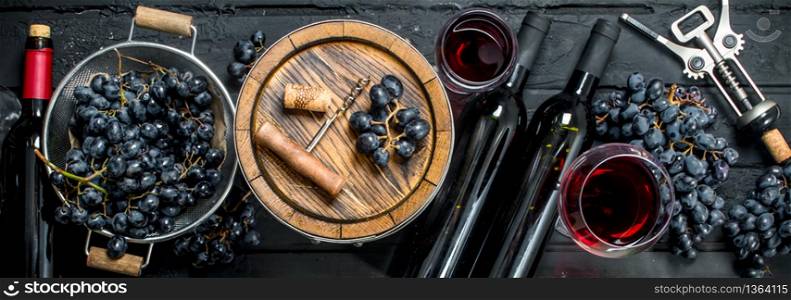 Wine background. Red wine with grapes and an old barrel. On a black rustic background.. Wine background. Red wine with grapes and an old barrel.