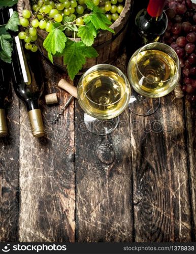 Wine background. White and red wine with branches of grapes. On a wooden background.. Wine background. White and red wine with branches of grapes.