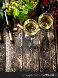 Wine background. White and red wine with branches of grapes. On a wooden background.. Wine background. White and red wine with branches of grapes.