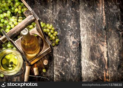 Wine background. White wine on a stand with branches of fresh grapes. On a wooden background.. Wine background. White wine on a stand with branches of fresh grapes.