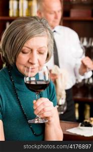 Wine bar senior woman smell wine glass in front of bartender