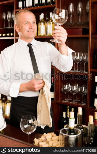 Wine bar waiter looking at clean glass in restaurant