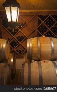 Wine Barrels and Bottles in Dimly Lit Cellar.