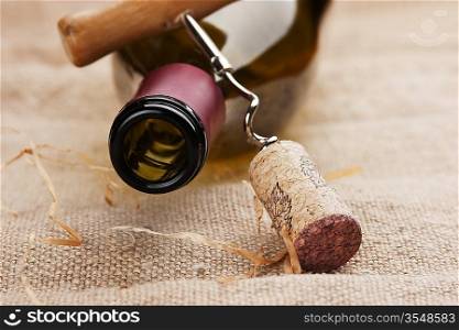 wine bottle and corkscrew on a canvas, still life