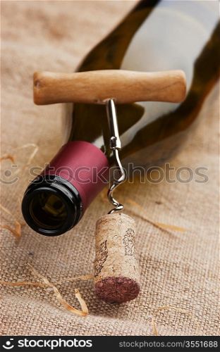 wine bottle and corkscrew on a canvas, still life
