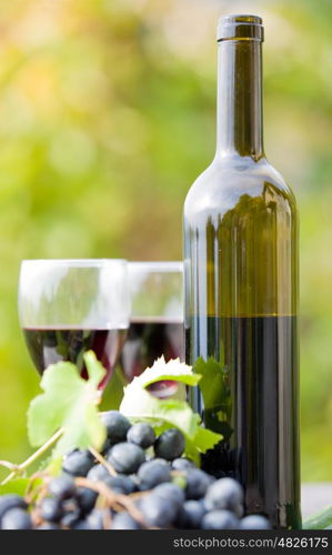 wine bottle and grapes on wooden table outdoor